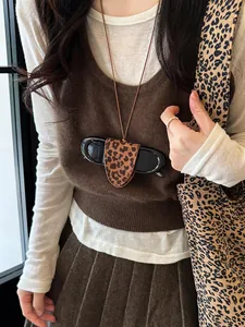 Close-up detail of a leopard print leather sunglasses holder necklace worn on a brown vest