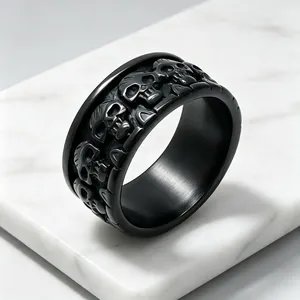Détail en gros plan d'une bague en acier noir avec sculpture gothique de crânes
