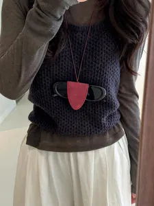 Red leather sunglasses holder necklace accessory worn on a stylish knit sweater