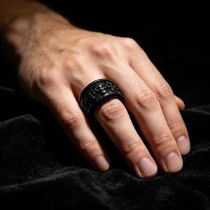 Gros plan d'une bague pour homme en acier noir avec des gravures détaillées de têtes de mort