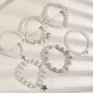 Detailaufnahme eines mehrlagigen Kristall- und Perlenarmband-Sets mit Stern- und Kreuzanhängern