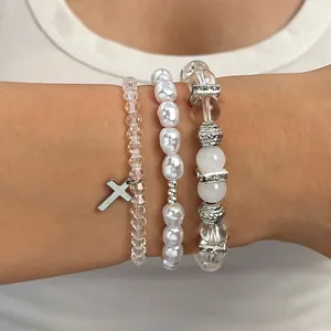 Detailansicht des mehrlagigen Kristall- und Perlenarmband-Sets mit silbernem Kreuz.