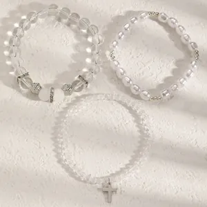 Detaillierte Makroansicht eines dreiteiligen Perlenarmband-Sets mit einem Kreuzanhänger