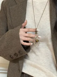 Élégant collier avec pendentif en œil de tigre vintage porté sur un pull en maille crème