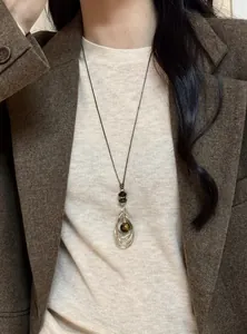 Gros plan d'un collier pendentif oeil de tigre vintage porté avec un blazer