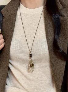 Gros plan d'un collier en œil de tigre rétro porté avec un blazer marron à chevrons
