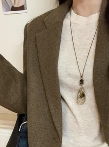 Vue détaillée d'un collier rétro en œil de tigre porté sur un blazer très élégant