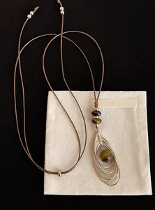 Gros plan d'un collier vintage en œil de tigre avec cordon brun et pendentif goutte
