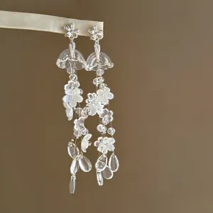 Vue détaillée d'élégantes boucles d'oreilles pompons muguet avec accents floraux.