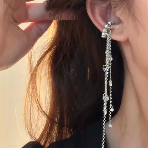 Detailansicht eines eleganten silbernen Quasten-Ohrclips mit weißen Perlen am Ohr