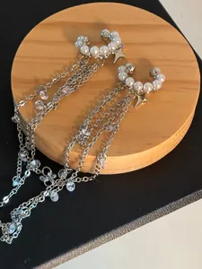 Detailansicht eleganter silberner Quasten-Ohrclips mit weißen Perlen und Sternanhängern