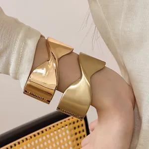 Elegantes brazaletes abiertos de metal retorcido geométrico en oro mate y brillo.