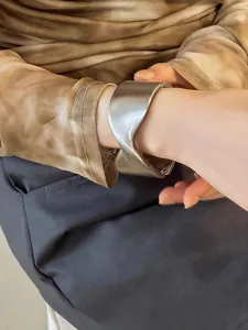 Primer plano de un elegante brazalete cruzado geométrico de plata mate en la muñeca