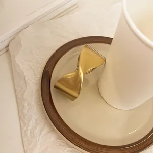 Primer plano de la textura de oro mate de un brazalete abierto retorcido geométrico