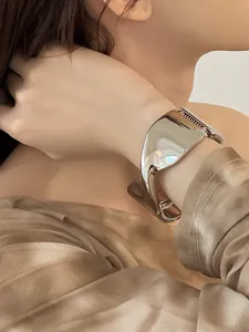 Primer plano detallado de un brazalete abierto metálico geométrico plateado ancho