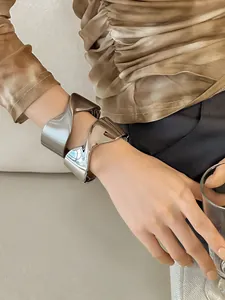 Primer plano de pulseras de metal retorcido geométrico mate y pulido en la muñeca