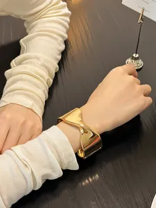 Primer plano detallado de un brazalete geométrico dorado retorcido en una muñeca