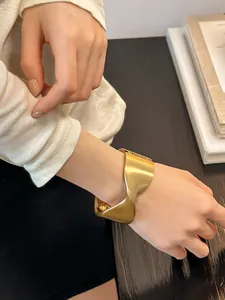 Primer plano detallado de un brazalete geométrico de oro mate usado en la muñeca
