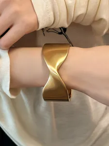 Vista detallada de un brazalete abierto geométrico de oro mate de diseño moderno