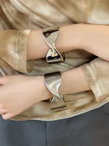 Primer plano del brazalete abierto de metal plateado con diseño geométrico en el modelo