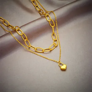 Detail view of double-layered gold-plated necklace with a heart-shaped lock pendant