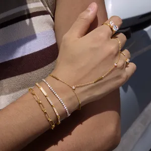 Détail de bracelets en acier doré 18 carats et bagues en zircon superposés sur une main