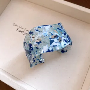 Chic blue and white marbled acrylic cuff bracelet featuring elegant floral cut-out patterns