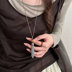 Detail of New Chinese style silver tassel necklace with beaded accents on brown cord