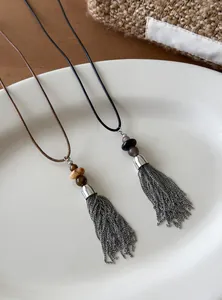 Close-up of silver tassel necklaces with beaded accents and thin cord straps