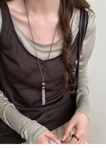 Detailed view of a New Chinese style long necklace with silver tassels and beads on model
