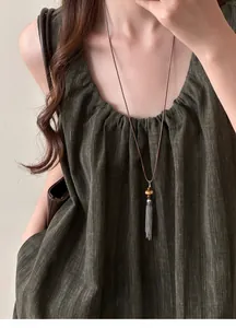 Elegant long silver tassel necklace with beads worn on a green textured dress detail