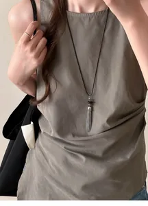 Detail view of a silver tassel beaded necklace worn as a minimalist long sweater chain.