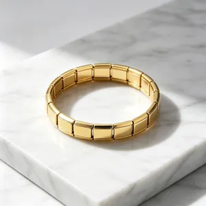 Gros plan d'un bracelet modulaire italien doré poli sur un socle en marbre blanc
