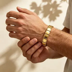 Zoom sur un bracelet à maillons modulaires italien doré porté au poignet d'un homme.