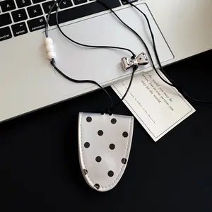 Close-up detail of leather polka dot pendant necklace featuring metallic bow tie element.
