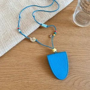 Close-up of blue leather glasses case necklace with cute shell and star charms