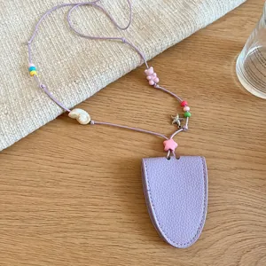 Close-up detail of the purple leather glasses pouch necklace with decorative beads and charms.