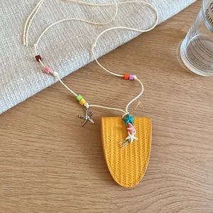 Close-up of yellow leather pouch pendant necklace featuring colorful beads and starfish charms