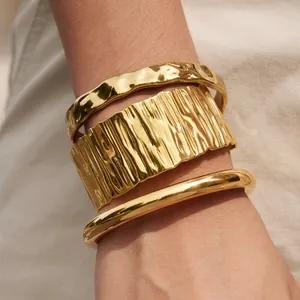 Dettaglio di alta qualità di tre bracciali rigidi in acciaio al titanio dorato sovrapposti