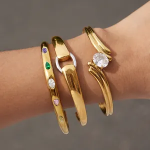 Primo piano di tre braccialetti in acciaio inossidabile dorato con pietre cz colorate