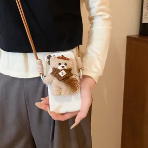 Detailed macro view of a cute plush bear phone case featuring a brown woven crossbody strap charm