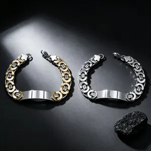 Nahaufnahme von zwei schweren Titanstahl-Armbändern in Gold und Silber mit Gravurplatten.