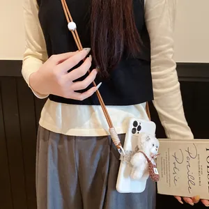 Close-up of a brown woven phone strap with a cute plush bear charm worn cross-body.