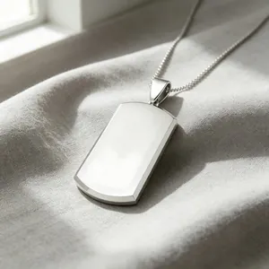 Close-up of a blank polished titanium steel military dog tag pendant on a gray fabric.