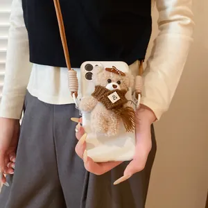 Detail view of plush teddy bear pendant with brown scarf and woven lanyard for phone