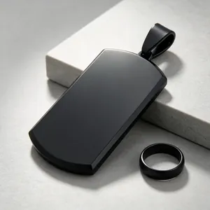 Macro view of matte black titanium steel dog tag pendant and matching ring on stone