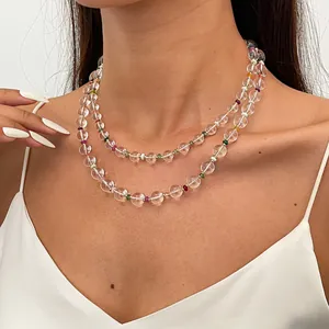 Detailed view of a double-layered clear glass beaded necklace on a model wearing white.