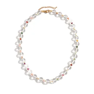 Minimalist necklace featuring clear glass beads and colorful accents on a gold chain
