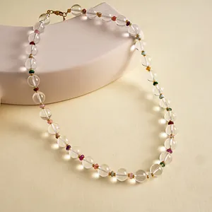 Detailed view of clear glass bead necklace with colorful accents on beige background