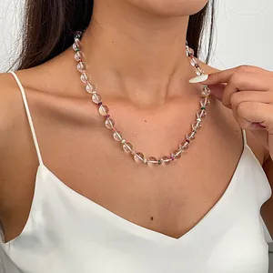 Close-up of a minimalist necklace with clear and colorful beads on a model's neck.